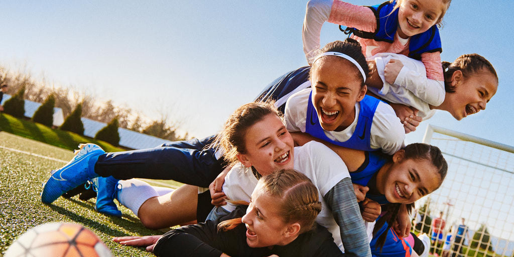 pile up of smiling girls on a soccer field